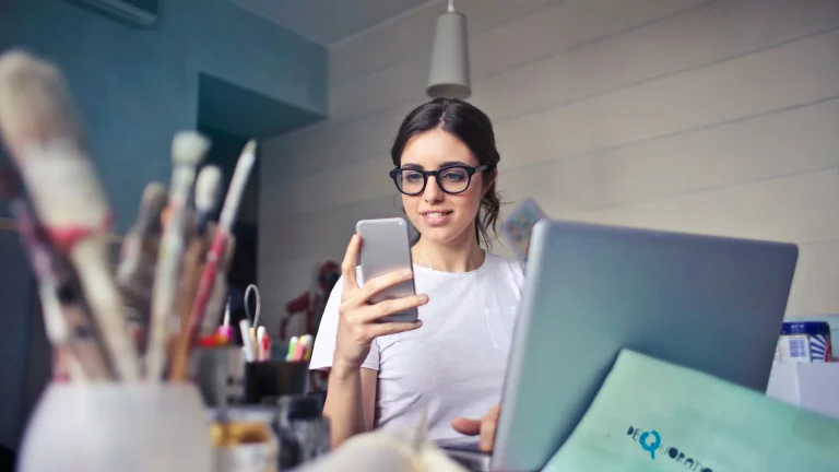 Cotygodniowy informator podatkowo-kadrowy na platformie szkoleniowej – kobieta patrzy w smartfon przy laptopie