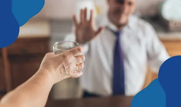 Zwolnienie dyscyplinarne pracownika leczącego się na chorobę alkoholową – mężczyzna gestem odmawia podawanej szklanki