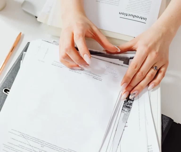 Kompendium kadrowe dla JSFP 2026 – dłonie przeglądają plik wydrukowanych dokumentów na segregatorze