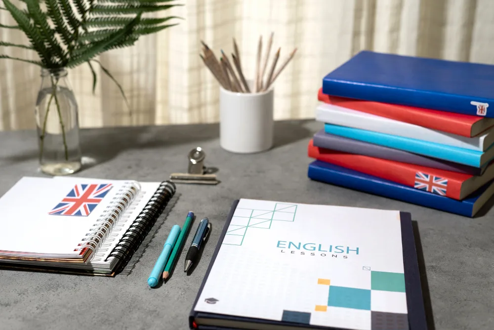 Notatnik English Lessons i kolorowe zeszyty do nauki języka angielskiego na biurku