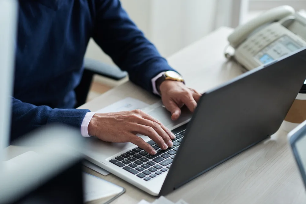 Mężczyzna pracujący na laptopie w biurze, ucząca się języka angielskiego w praktyce zawodowej